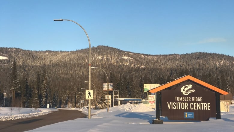 Snow in the streets of a mountain town with a sign advertising it's visitor centre.