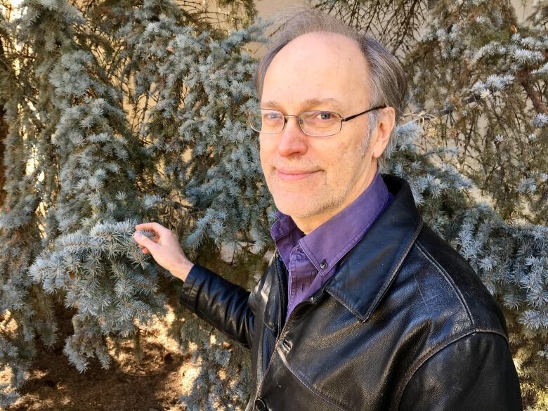 A man touches a tree branch.