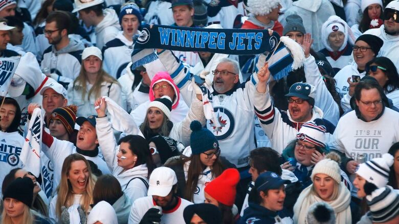 A crowd of hockey fans pack the street, all wearing white.