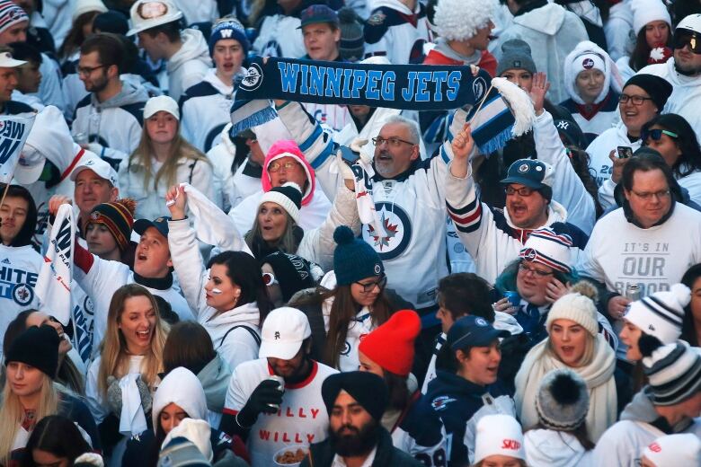 A crowd of hockey fans pack the street, all wearing white.