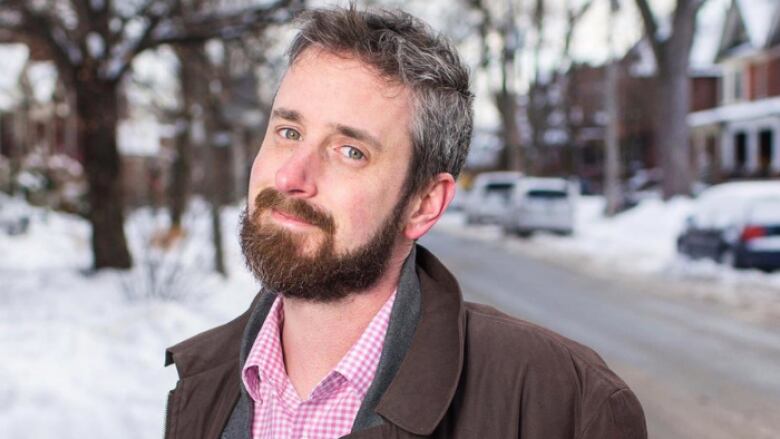 A caucasian man wearing a brown jacket mugs for the camera.