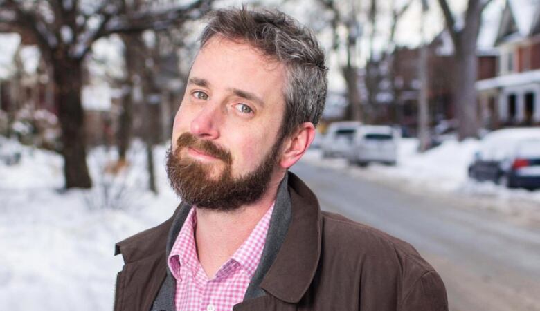 A caucasian man wearing a brown jacket mugs for the camera.