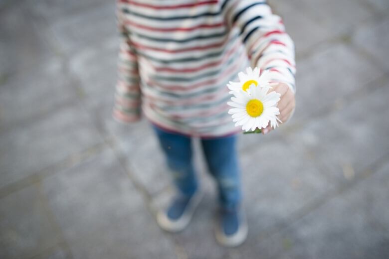 A child presents two white flowers