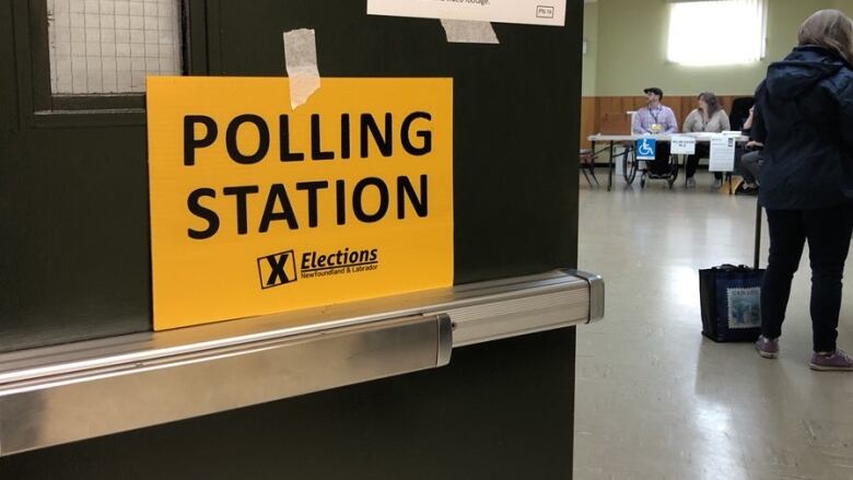 An orange sign taped to a door reads polling station.