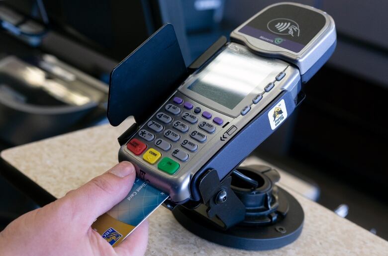 Someone is shown using a debit card machine to make a payment. 