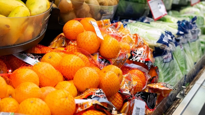 Oranges, mangoes, kiwis and lettuce are pictured in a grocery store cooler.  