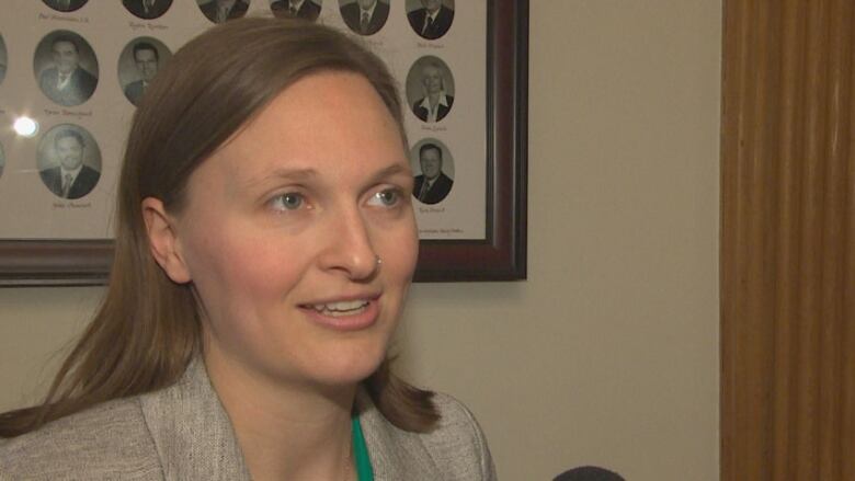 A photo of a woman with light brown air speaking to a reporter.