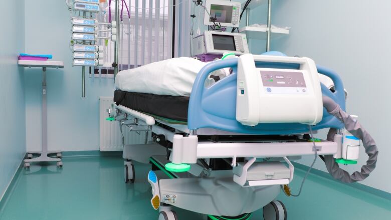 An hospital bed in a blue-painted room.