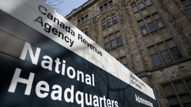 A sign saying 'Canada Revenue Agency' is seen outside a large stone building.