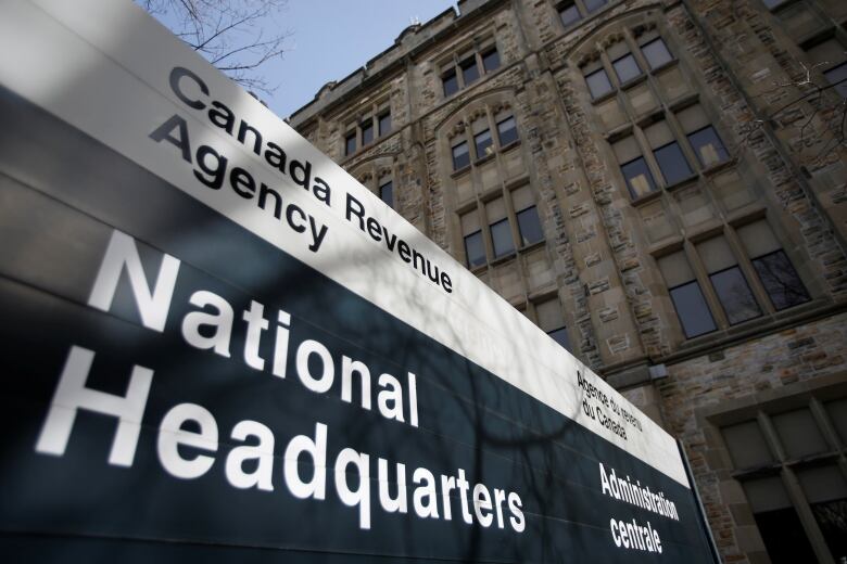 A sign saying 'Canada Revenue Agency' is seen outside a large stone building.