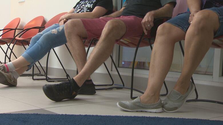 People shown from the waist down sitting in a waiting room.