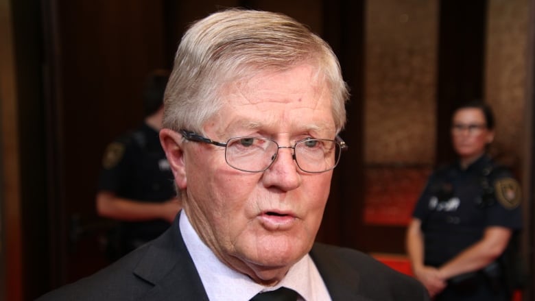 A man wearing glasses is shown in a shirt and tie.