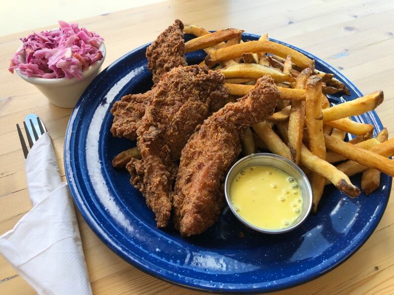 A plate filled with fries, fried chicken and a bright yellow sauce.