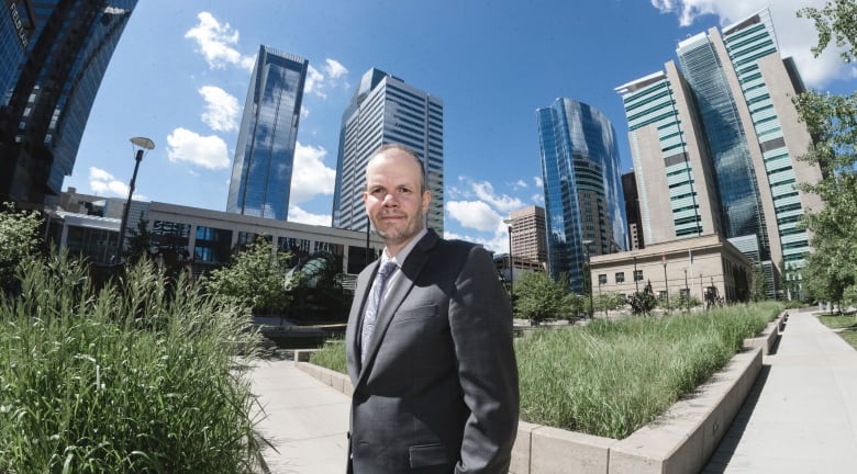 Man stands in front of buildings, pictured from below. 