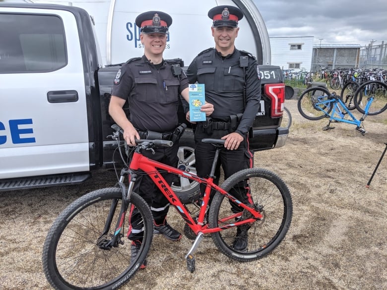 two police offices smiling in front of a bike