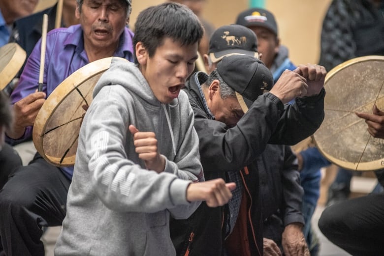 A group of people drumming and playing Dene handgames.