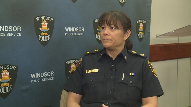 Pam Mizuno sitting in front of a police backdrop.