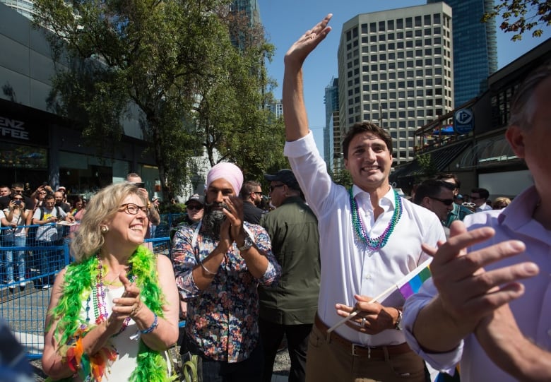 A crowd of people march in a parade as onlookers cheer.