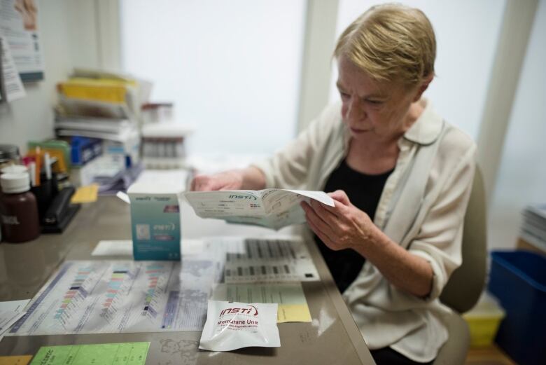 A woman sits at a desk and reads through an information packet