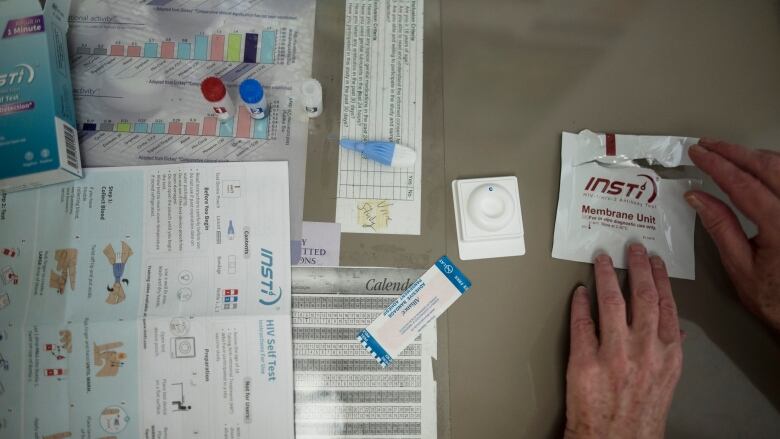 A hand is shown tearing open an INSTI rapid HIV self-test