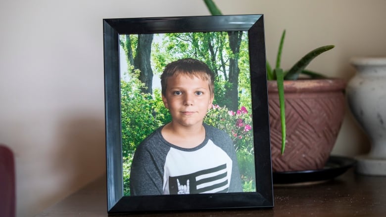 A picture at his grandfathers home of Carson Crimeni in Langley, British Columbia on Aug. 9, 2019. Carson is smiling in the photograph where he is shown from the shoulders up in front of a garden. He has blonde hair and looks about 12 in the picture.