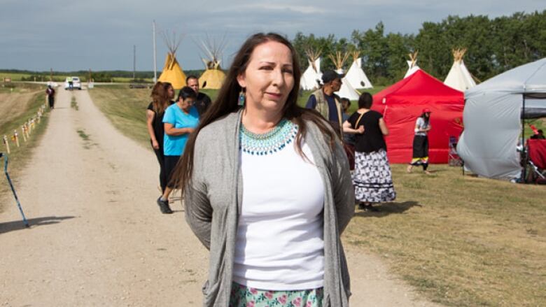 A woman standing in front of a field with teepees.