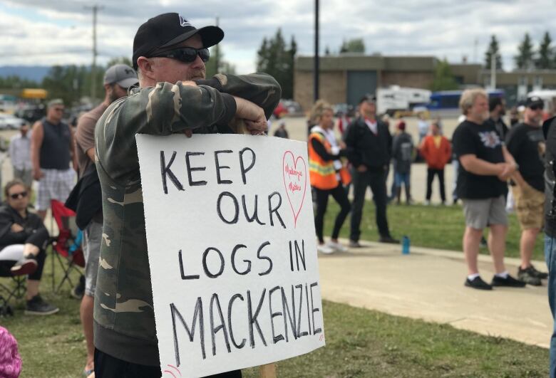 A man stands with a sign that reads: 'Keep our logs in MacKenzie.'