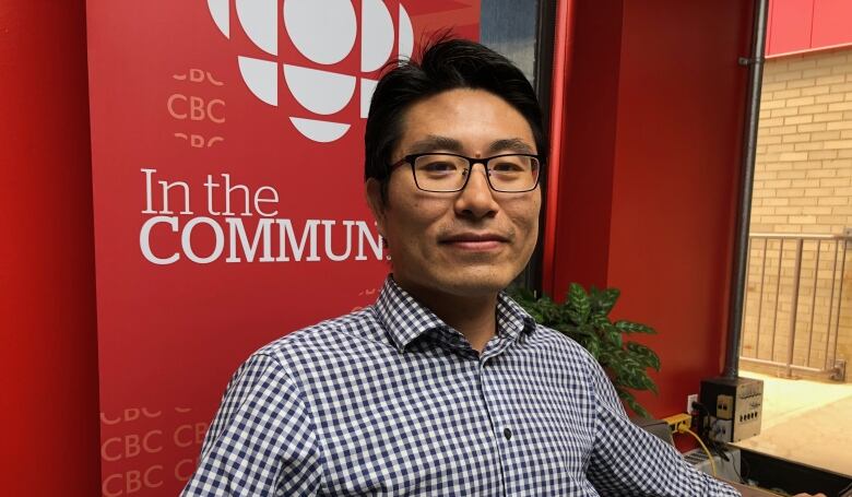 Xander Wang sitting in front of sign with CBC logo.