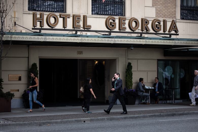 Pedestrians walk in front of Hotel Georgia in Vancouver.