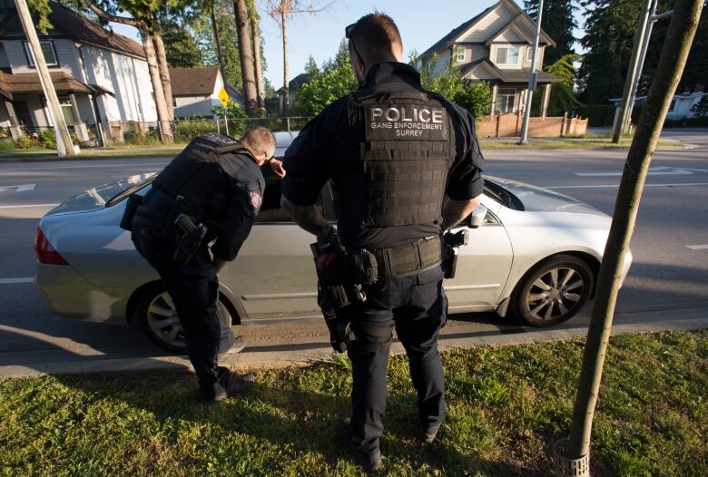 Two police officers speak to the driver of a car.