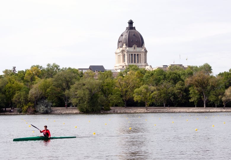 Saskatchewan's legislature can be seen over a lake, with a kayaker on the water.