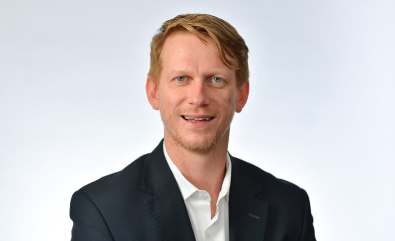 Man with red hair wearing black jacket and white shirt. 