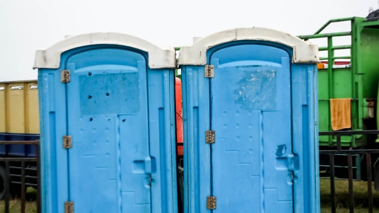 Two generic looking blue porta-potty washrooms. 