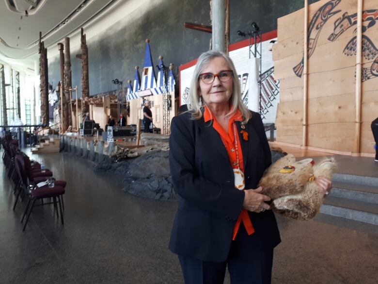 A woman holds a rattle wrapped in a beaver pelt