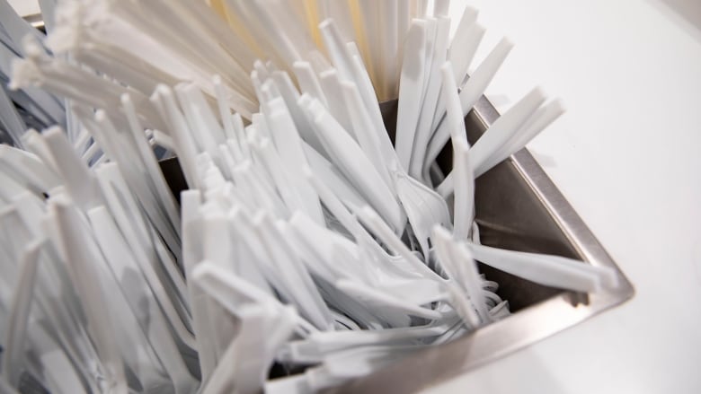 A bin filled with plastic spoons and forks.