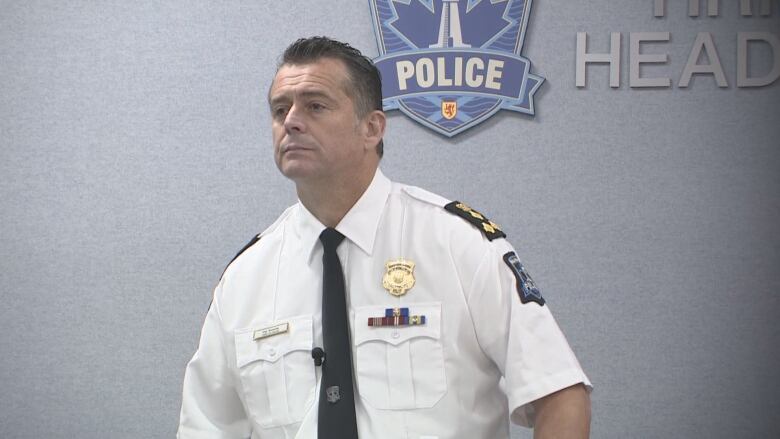 A man in a police uniform stands at a podium.