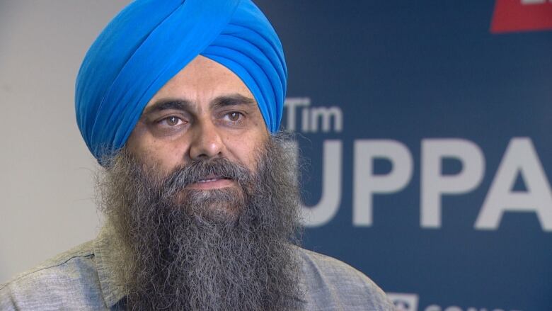 Photo of Tim Uppal in front of his campaign sign.