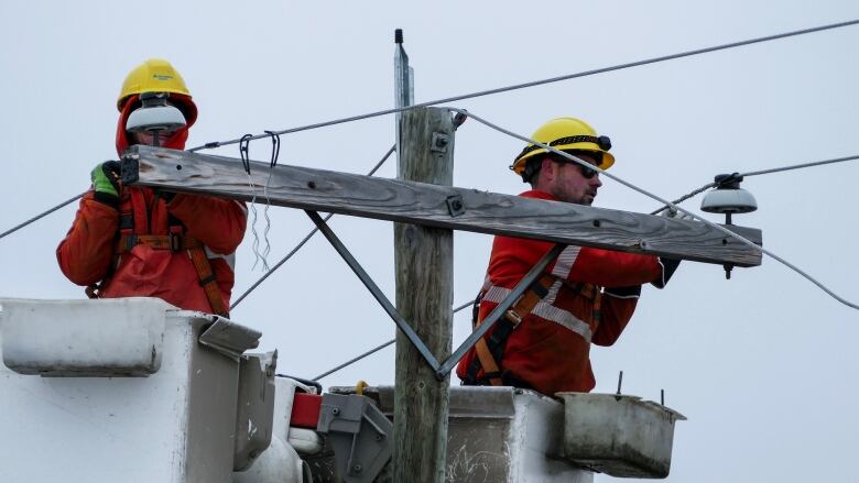 Hydro workers make repairs at the top of a Hydro pole.