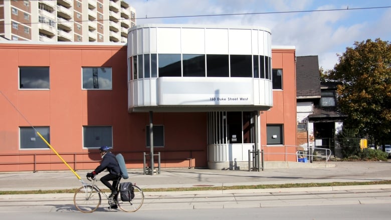 An orange and white building on a city street during the day. A biker rides past.