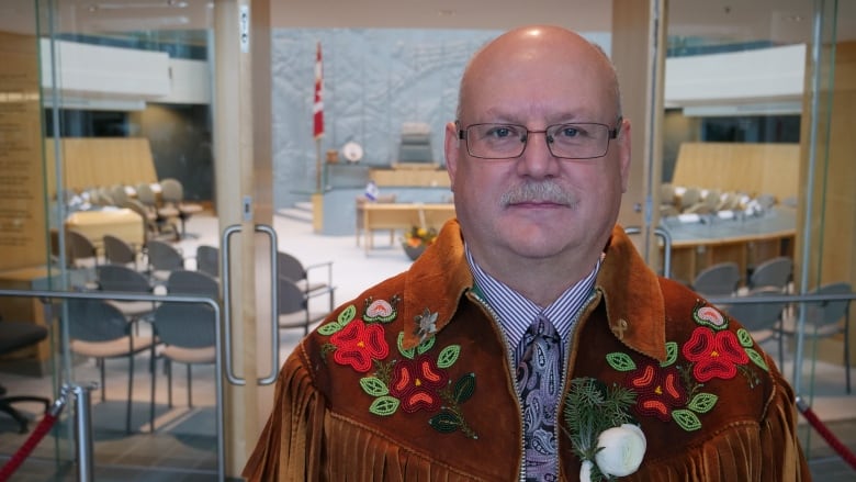 A portrait of a man in a beaded moose leather jacket.