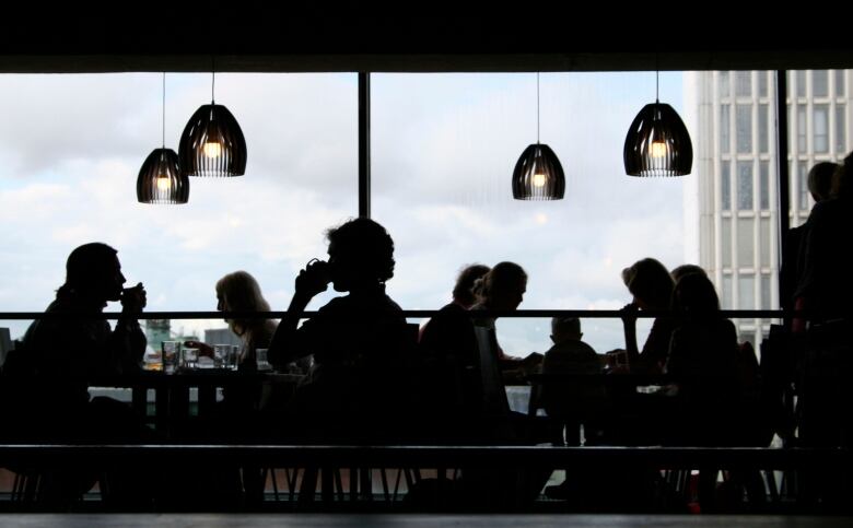 The silhouettes of diners at a restaurant are pictured.