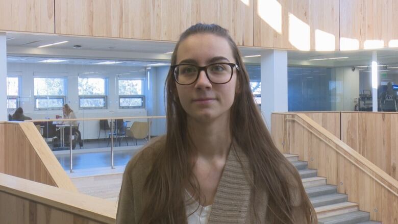 A young woman in glasses stands in a study area at Laurentian University.