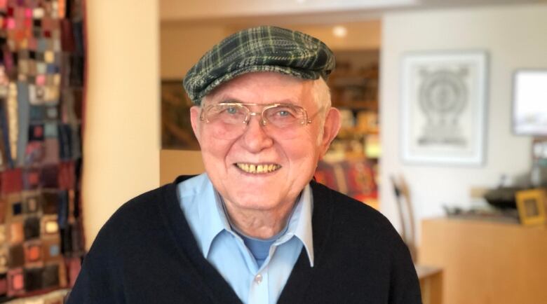 An elderly man smiles inside a home