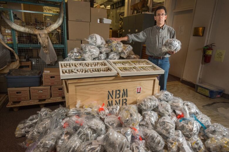 A serious-looking man poses with many dead birds. 