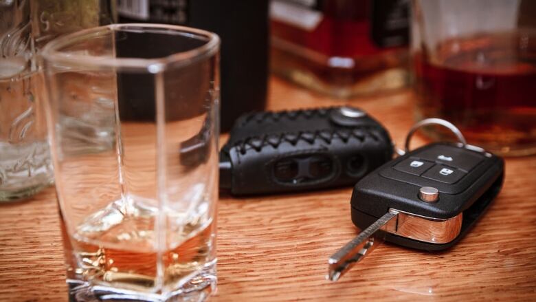 A car key next to a glass of alcohol.