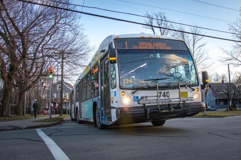 A number 1 Halifax transit bus is seen driving though an intersection.  The sign on the top reads 'Spring Garden Road to Mumford Terminal'.