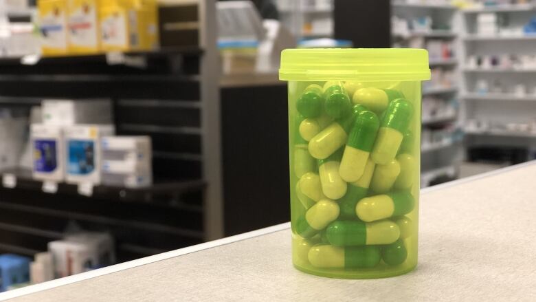 A generic yellow prescription drug bottle is filled with pills.