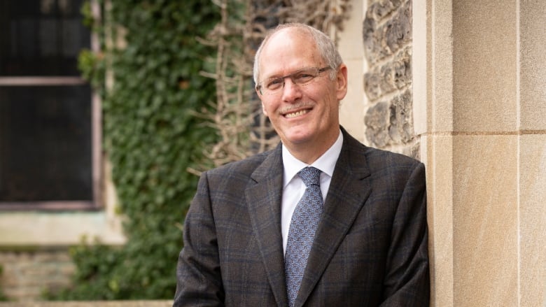 A portrait of a man in a suit outside.