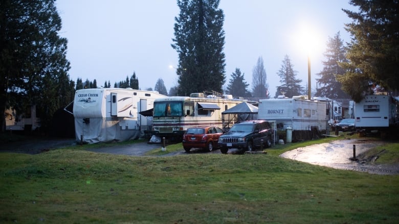 RVs parked close together near a field at dusk.