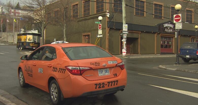 An orange taxi parked on a downtown street. 